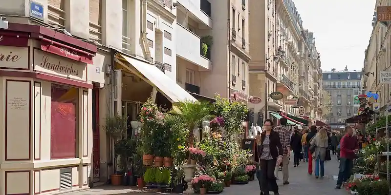 Street scene in a Paris neighborhood with classic buildings and trees.