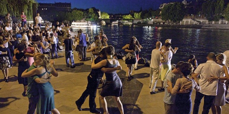 On warm Paris evenings there is dancing at Jardin Tino Rossi and here we see dancers with a river boat in the distance