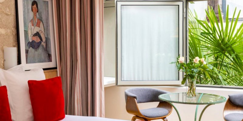 A cozy room at Hotel du Jeu de Paume with greenery outside the window