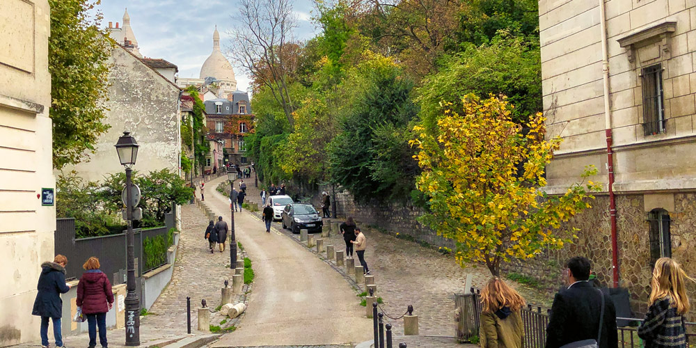 A street in Montmartre with Sacré Coeur in the distance, photo by Mark Craft