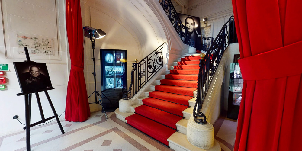 A red carpeted stairway rises Inside Studio Harcourt