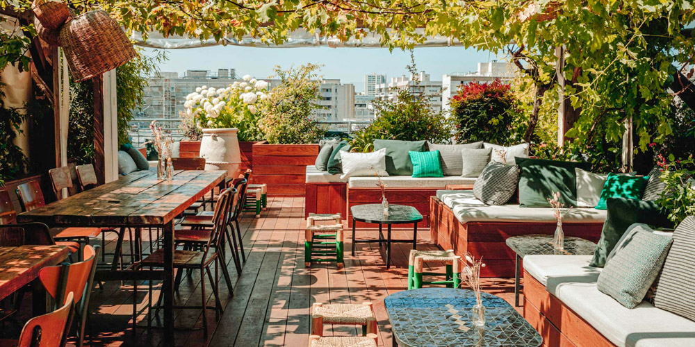 The rooftope bar at Le Perchoir with tables, cozy sofas, and Paris city views