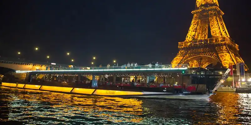 Bateaux Mouches dinner cruise Paris at night with illuminated Eiffel Tower sparkling on Seine River