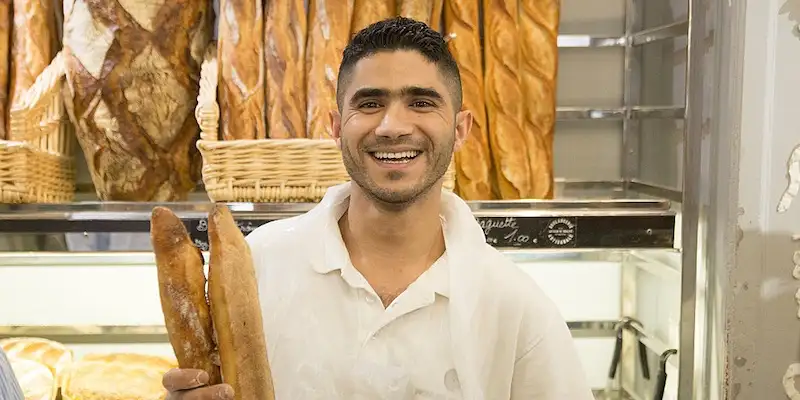 A recent winner of The Best Baguette in Paris smiles in front of his baking