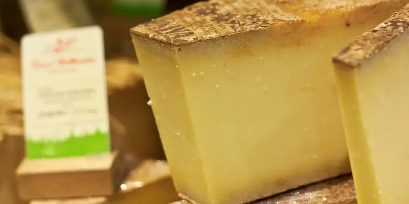 Large chunks of Comte overflow on a cheese counter