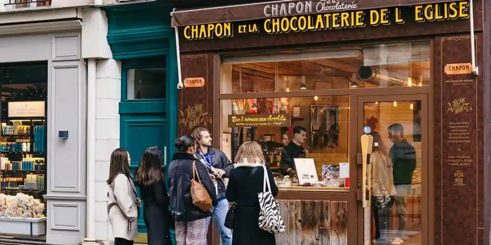 Visitors gather outside a chocolatier during a Saint-Germain food tour