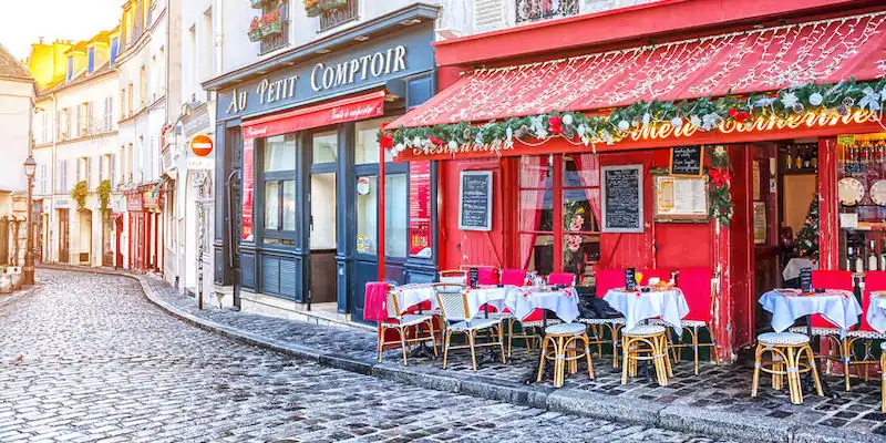 A cobblestone steet in Paris with shops decorated for the holiday season A cobblestone steet in Paris with shops decorated for the holiday season