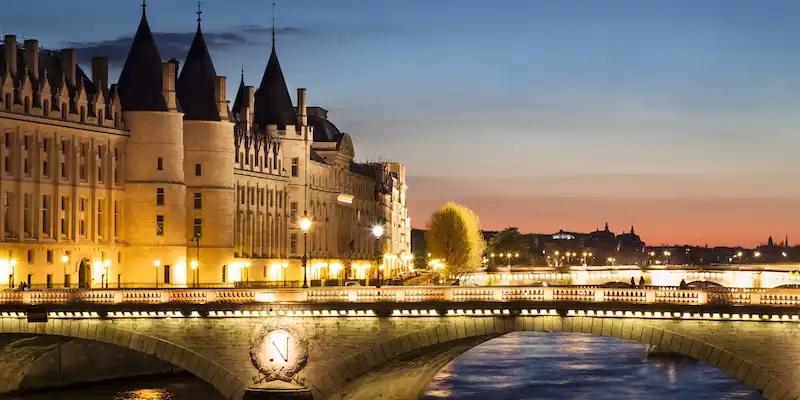 The imposing towers of La Conciergerie overlook the Seine River at night