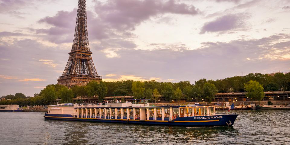 A bateau cruises the Seine river beneath the Eiffel Tower