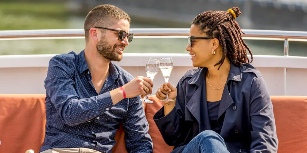 A couple clink glasses on Champagne Seine River Cruise in Paris