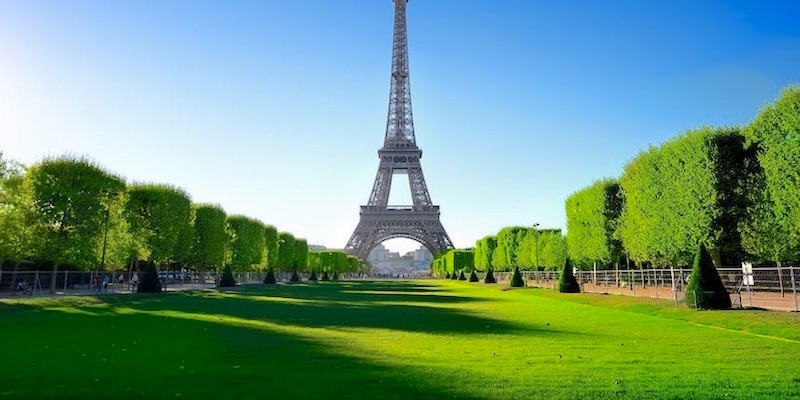 The expansive green lawn of the Champ de Mars, at the foot of the Eiffel Tower
