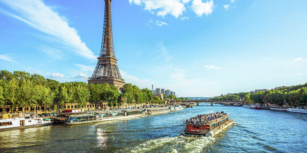 A river cruise boat sails past the Eiffel Tower: both are included in a combo tour