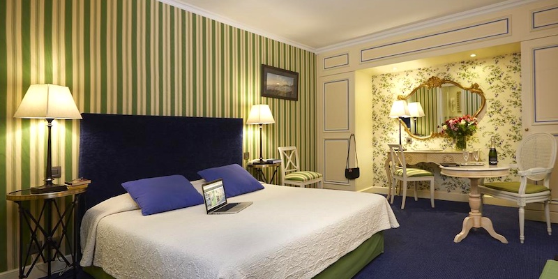 A room at Hotel Beaubourg decorated with green-and-yellow striped wallpaper in th Marai Paris