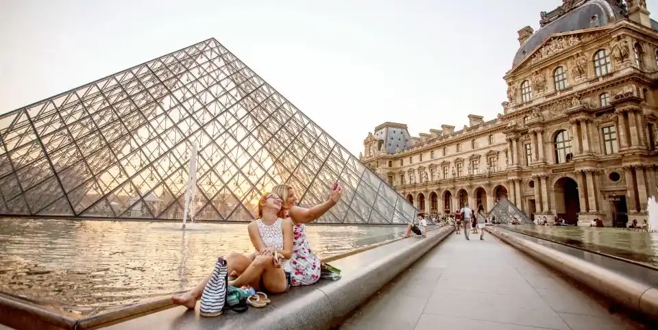 Two women taking a selfie at the Louvre Pyramid