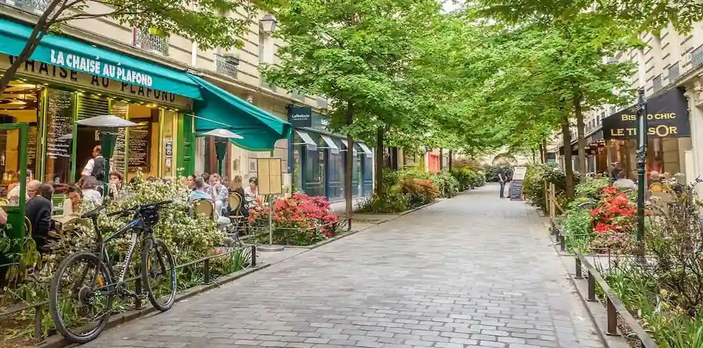 A Paris street with cafés, shops, and tree-lined walkway