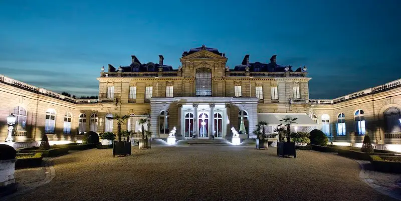The courtyard and wings of Musee Jacquemart Andre, lit at night. There are palm trees!