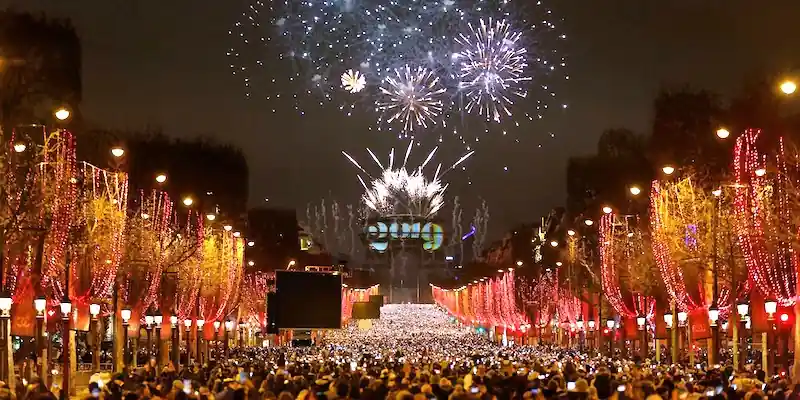 Crowds celebrate New Year's Eve on the Champs-Élysées beneath the Arc de Triomphe