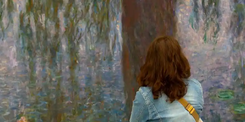 A woman studies a panel of Monet's lily pond paintings