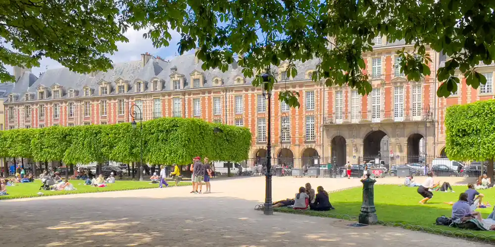 Place des Vosges in the Marais, Paris, with people relaxing in the square