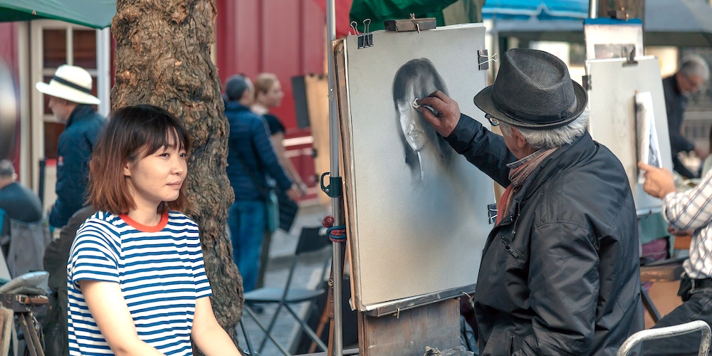 An artist working on a portrait at Place du Tertre, photo Wikimedia by John Gillespie