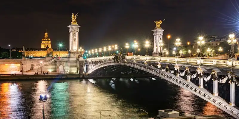Pont Alexandre III dramatically lit at night, with Les Invalides in the distance