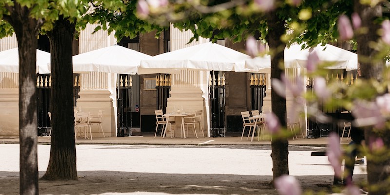 White umbrellas and chairs on the terrace at restaurant Palais Royal