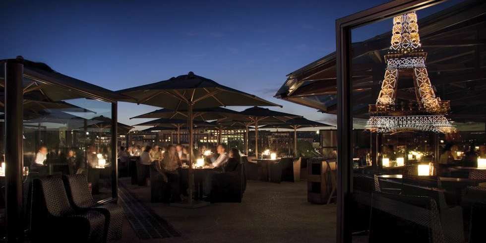 Diners at restaurant Les Ombres with the lighted Eiffel Tower right next door