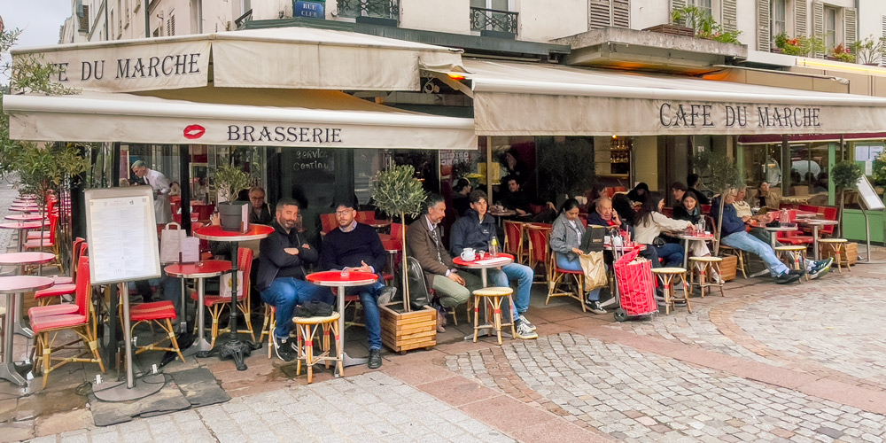 Afternoon diners seated at the signature red tables of Cafe du Marche on Rue Cler, photo by Mark Craft