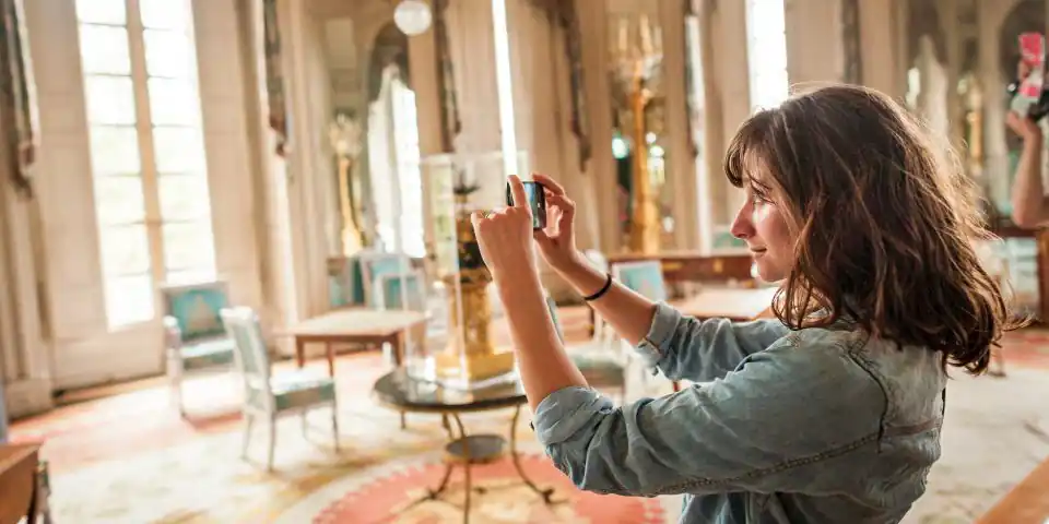 A visitor taking photos in the Chateau de Versailles on a private day trip from Paris