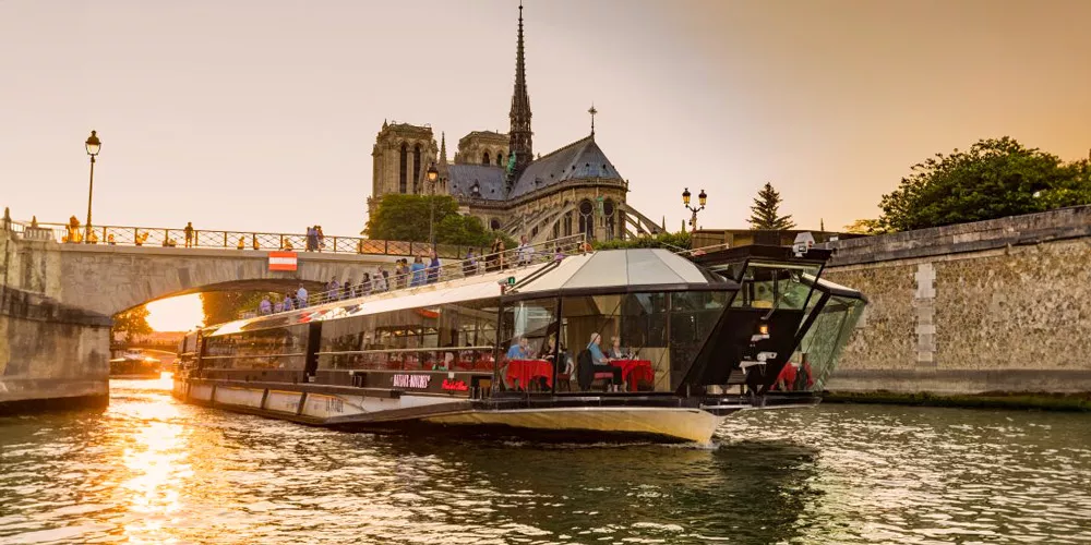 Bateaux Mouches Dinner Cruise boat sails beneath Notre Dame