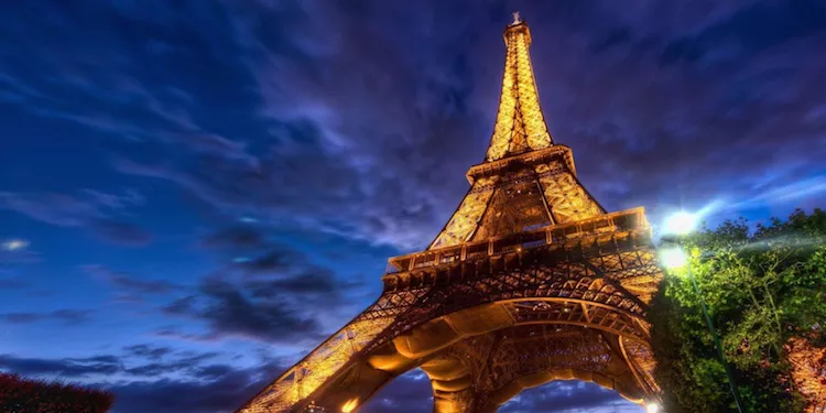 the Eiffel Tower lit at night against a dark blue sky