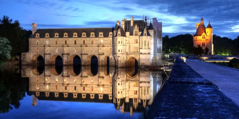 Chateau de Chenonceau in the Loire Valley beautifully lit at night, seen during a Day Trip From Paris